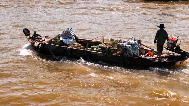 Vietnam farmer sailing a traditional wooden boat full of fresh fruits and vegetables on the mekong river delta, on the cai rang floating market