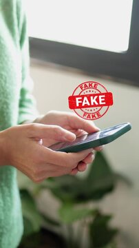 Person holding a smartphone with a fake news stamp appearing over the screen, symbolizing misinformation, disinformation, and the spread of untruths on social media and internet media