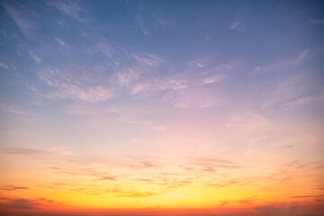 Fototapeta premium Beautiful sunrise sky with vibrant gradient orange and gold colors and soft blue, Clear atmosphere with wispy clouds. Peaceful, perfect for background and copy space, High resolution images