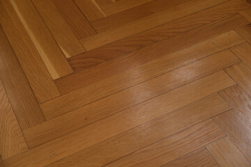 Wooden parquet floor with herringbone pattern in warm brown tones, showing texture and natural wood grain in indoor flooring design.