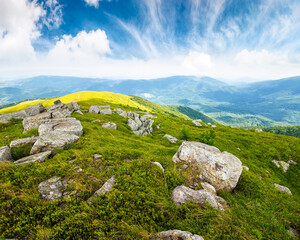 Fototapeta premium mountain landscape in summer with rocks. green grass under blue sky. alpine meadow and rolling hills with boulders on sunny day. environment sustainability and protection. background for earth day