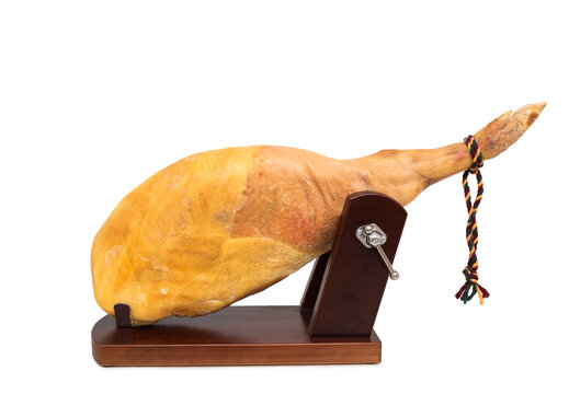Whole Iberian ham leg in a wooden ham stand isolated on white background