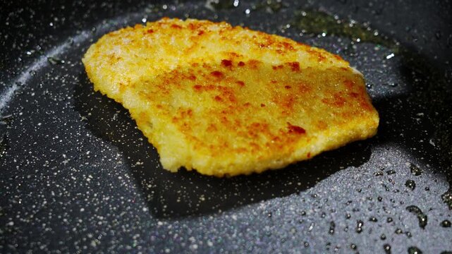 Frying white fish fillets. Frying hake fillets in a hot pan Breaded golden cutlet crisping in pan, closeup of breadcrumb coating turning deep golden as spatula presses gently, Selective focus
