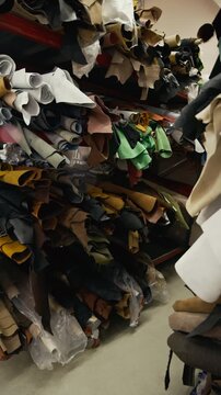 Vertical no people shot of colorful leather rolls placed on shelves in storage room of leathercraft studio, raw cowhide sides storing in backroom