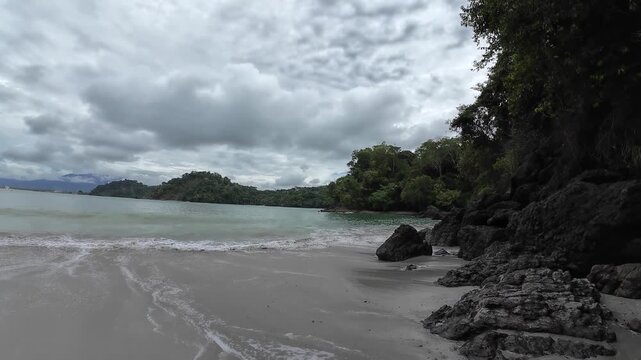 HD coastal video of Playitas Beach in Costa Rica featuring gentle waves rolling onto sandy shoreline beneath dramatic tropical clouds
