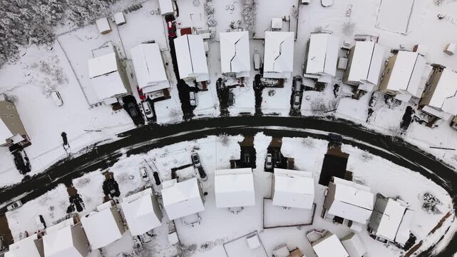 Aerial view: snow-covered country houses and streets in Ryan Beachville suburb of Halifax after overnight snowfall Canada. Thick white blanket on roofs and yards in clear daytime winter light 4K.