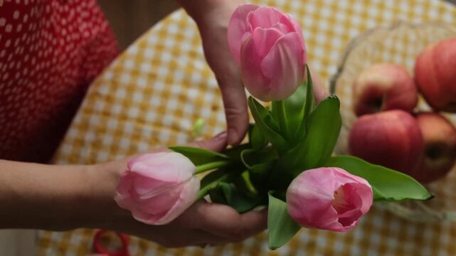 Mother's day or women's day. Female hands put a bouquet of tulips flowers in vase. Spring home decor.