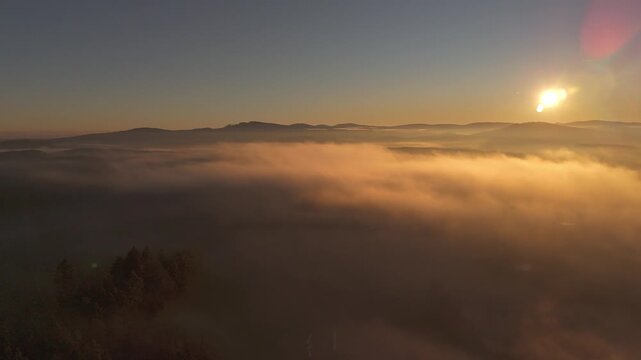 Aerial view of a sea of fog over morning countryside under clear sky with sun