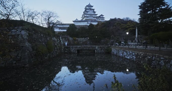 Pretty silhouetted reflection of 16th century Matsumoto castle in leaf covered pond in the morning - wide shot