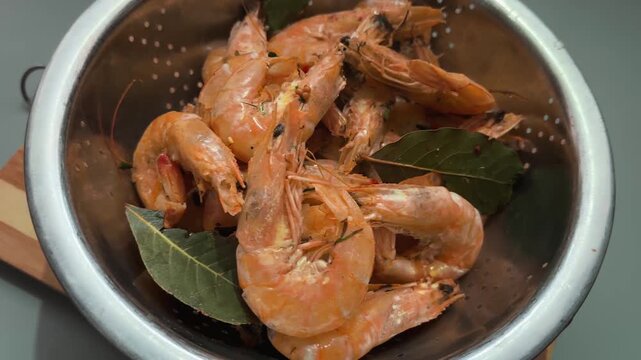 Freshly boiled unshelled king prawns in metal kitchen bowl