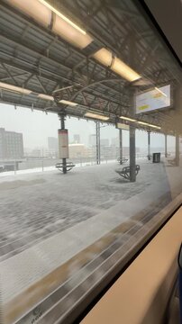 View from train window of snowy railway station platform with modern infrastructure and winter travel atmosphere