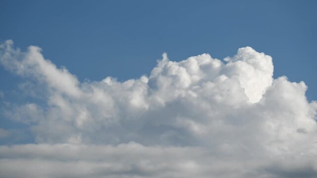 Time lapse of bright white cumulus clouds rising and drifting across a deep blue sky, growing and reshaping in steady wind currents.
