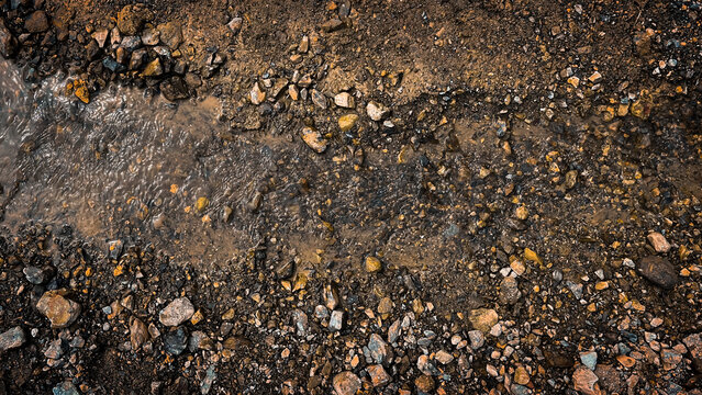 Overhead shot of a textured path with gravel and flowing water, rustic natural background