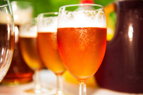 Glasses of beer arranged in a row on an outdoor table