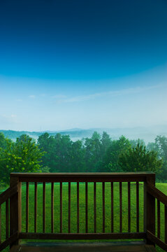 Lifting fog at sunrise over Helen, Georgia, seen from a balcony with a wooden railing