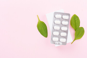 Plantain leaves with medicines on color background, top view