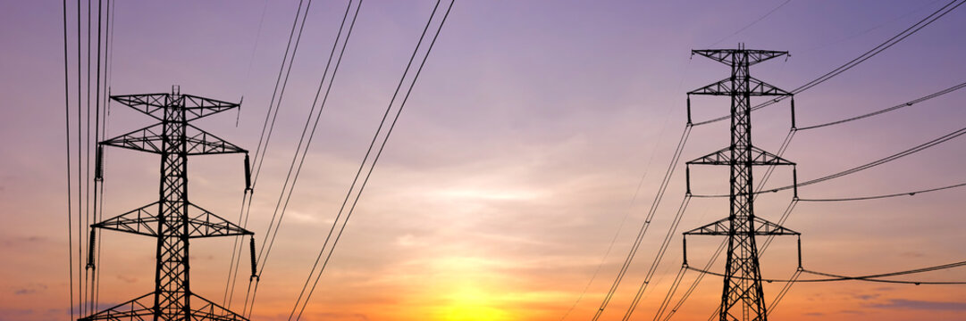 High-voltage power lines silhouetted against a beautiful sunset sky