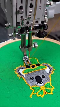 Embroidery machine creating a cute koala wearing a St. Patrick's Day hat and bow