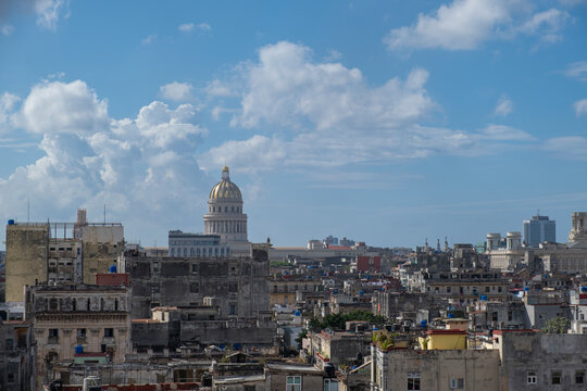 Aerial cityscape view of Havana City, Cuba - restored golden Capitolio dome, colorful facades of old colonial buildings and shingled roofs, sunny day, blue sky with white clouds.