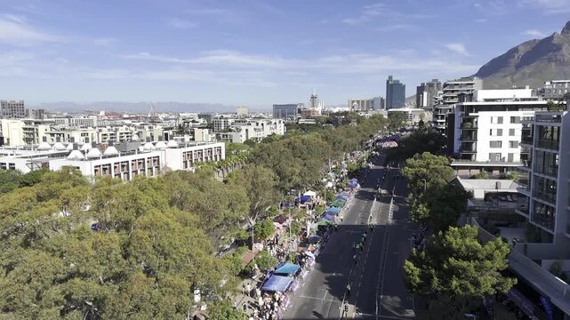 Drone rises up from main street during parade on sunny afternoon in Green Point, South Africa