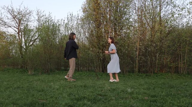 A loving couple in summer clothes walks through a summer park field in nature.v