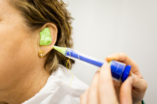 Detail of a senior woman having custom-made earplugs fitted at a specialized ear clinic. Concept of earplug manufacturing for noise, sleeping, or water.