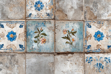 Aged tiles adorned with blue and orange floral patterns show wear and tear over time