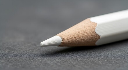 Close-up of a white colored pencil tip on a textured gray background, showing wood grain