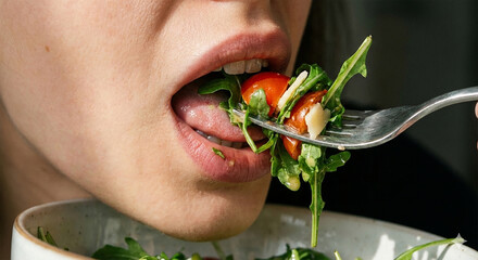 Close-up of a woman&acute;s mouth eating a vegetarian salad