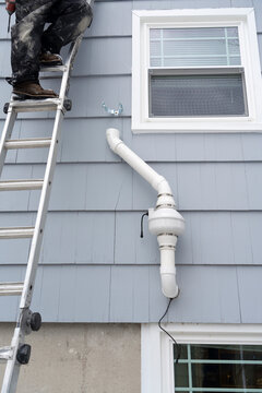 manual worker installing radon mitigation system outside the house