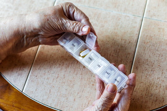 Close up senior woman hands holding weekly pill organizer with tablets sorted by days, concept medication schedule, healthcare management, elderly treatment, chronic disease control pharmacy home care