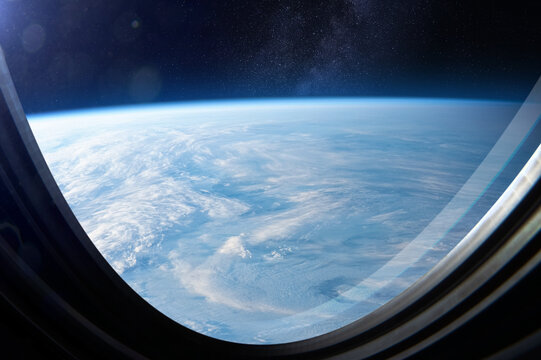 Amazing planet Earth and the Milky Way galaxy. Earth surface is covered in clouds. Earth through spacecraft porthole, space exploration. 