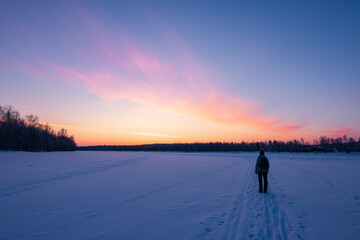 Sunset over frozen Lake Inari with snow covered trees in Lapland, Finland near Ivalo