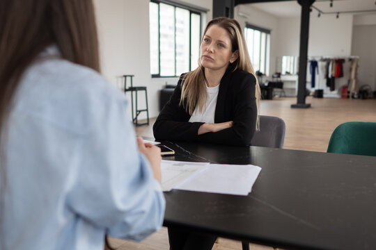 Businesswoman with strong emotional expression listening attentively while having a serious business conversation or job interview with a colleague or job applicant in a modern office