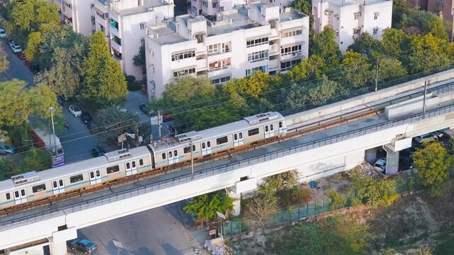 Top down view of The Delhi Metro is running on the tracks towards the Blue Line and Pink Line. Delhi Metro train. Cinematic drone shot of Metro rail in delhi.