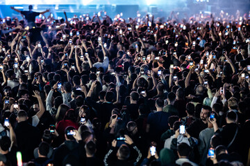 Crowd holding smartphones recording live concert