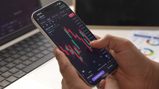 Stock Exchange Broker Analyzing Real-Time Stocks and Exchange Market Charts on Smartphone Using Online Trading App. Investment Agent Working in Office. Close Up.