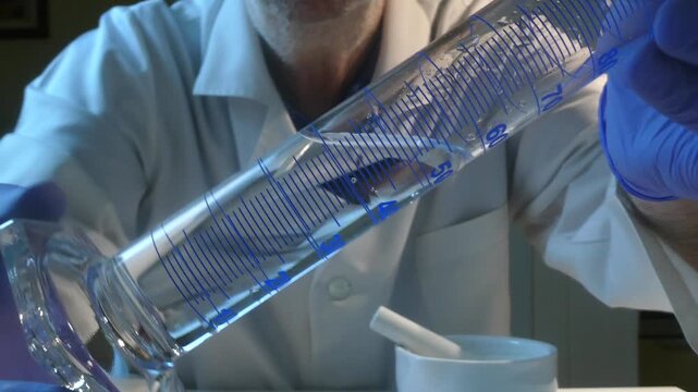 Scientist in lab coat holding graduated cylinder