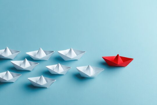 Creative pivot concept: paper boats in formation with a red outlier on blue backdrop