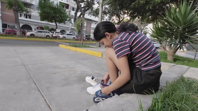 Teenage Girl Putting on Inline Skates in City Park