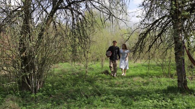 A loving couple in nature in the summer walks along a meadow in the forest