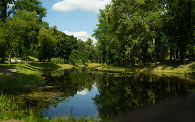 Obraz premium Scenic summer landscape of Oranienbaum park with calm river water, green trees and sky reflection in Lomonosov, Saint Petersburg.