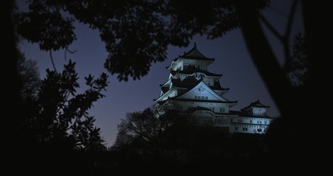 Glowing, ancient Japanese crow castle at dusk - low shot