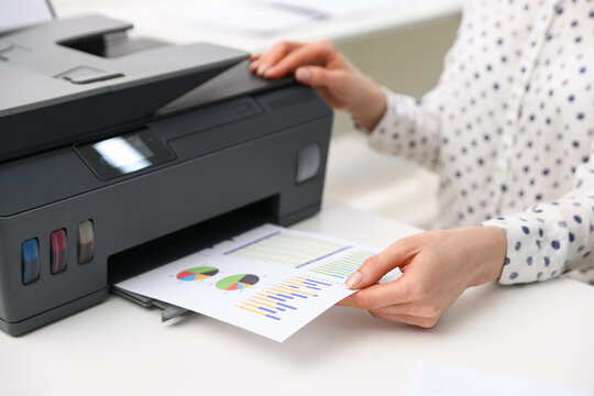 Woman using printer at white table indoors, closeup