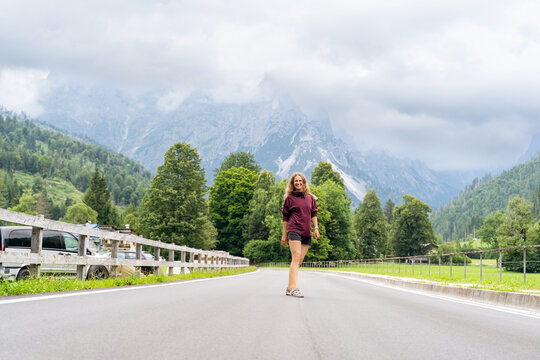 Woman walking on road with scenic mountain backdrop