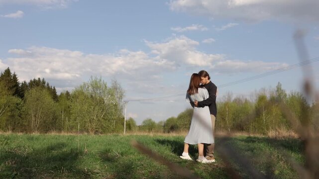 A loving couple in summer clothes walks through a summer park field in nature.v