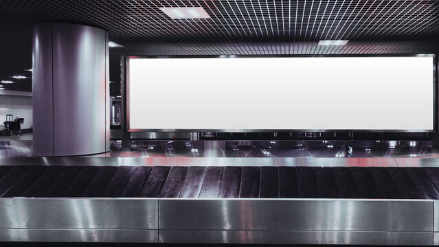 Large blank billboard mockup above airport baggage claim conveyor belt in modern terminal interior, glossy floor reflections, grid ceiling lights, copy space for advertising design