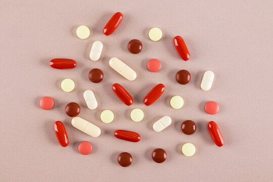 Assorted medicine pills and capsules on a pink surface