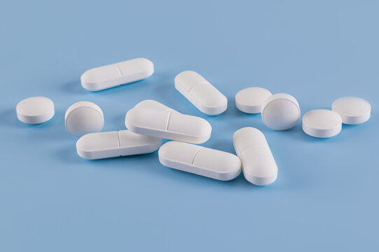 Assorted white pills on blue background