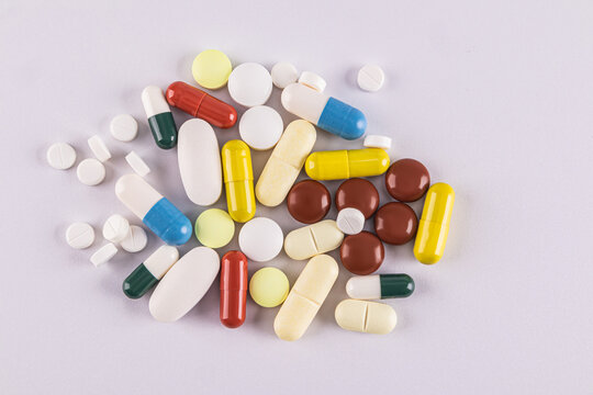 Various colorful pills and capsules on a light background